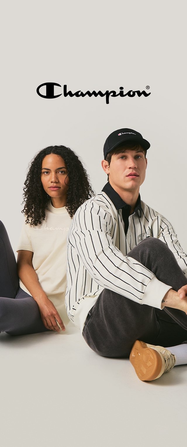 Twee personen zitten naast elkaar. De een draagt een beige t-shirt met een logo, de ander een gestreepte witte trui en pet.