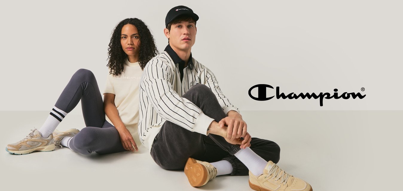 Muž a žena sedí zády k sobě na podlaze, oba mají na sobě neformální oblečení a béžové tenisky na jednoduchém světlém pozadí.