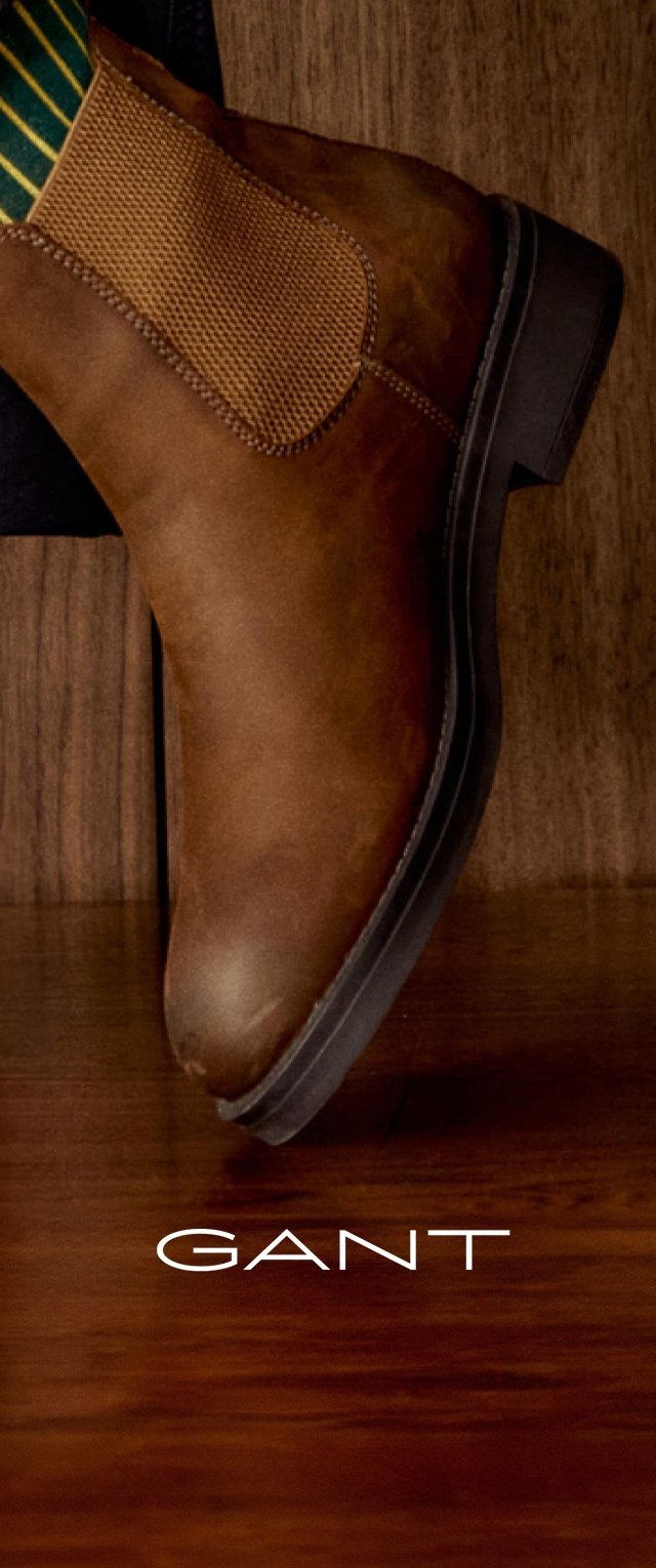 Braune Leder-Ankle-Boots mit elastischen Seitenstücken, runder Spitze und strukturiertem Profil. Auf einem Holz-Hintergrund präsentiert. GANT-Logo sichtbar.