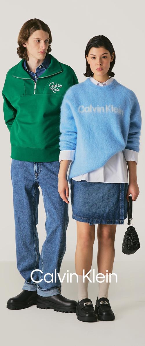 Pullover verde in pile con zip a un quarto, maglione blu peloso, gonna di jeans e jeans. Scarpe chunky nere e borsa testurizzata.