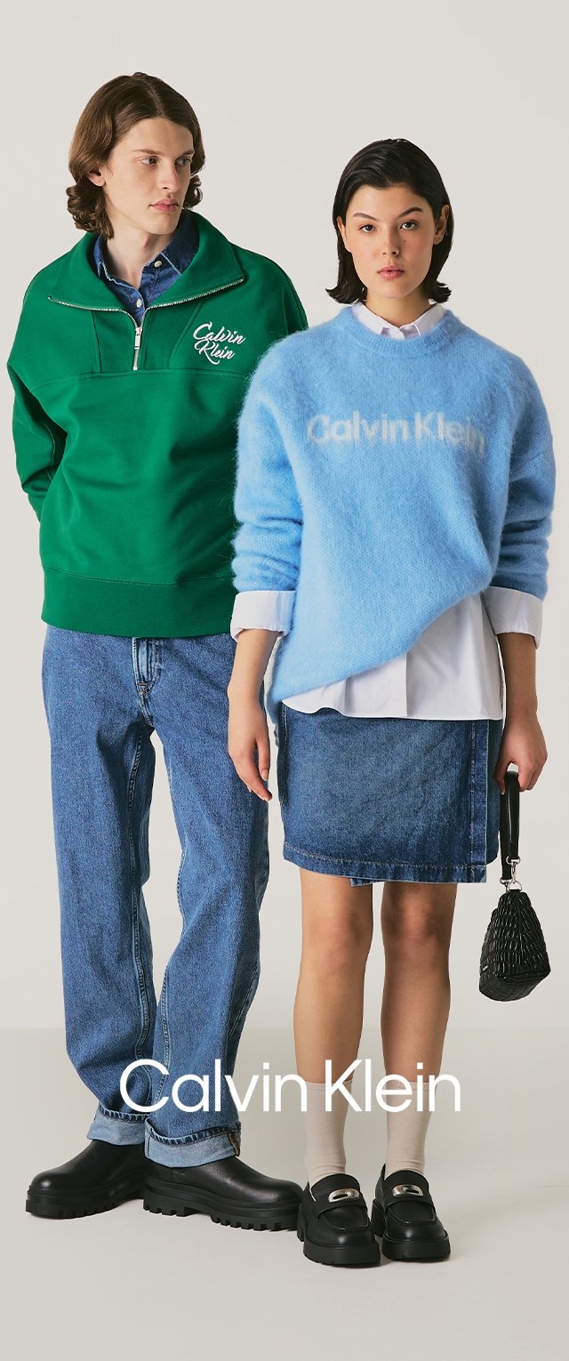 Sudadera de polar verde con cremallera de un cuarto, suéter azul de peluche, falda de mezclilla y jeans. Zapatos negros gruesos y bolso texturizado.