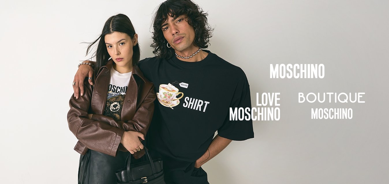 Mladý muž s kudrnatými vlasy v černém tričku s potiskem má paži přes ramena ženy, která nosí hnědý kabát, černou sukni a drží černou kabelku.