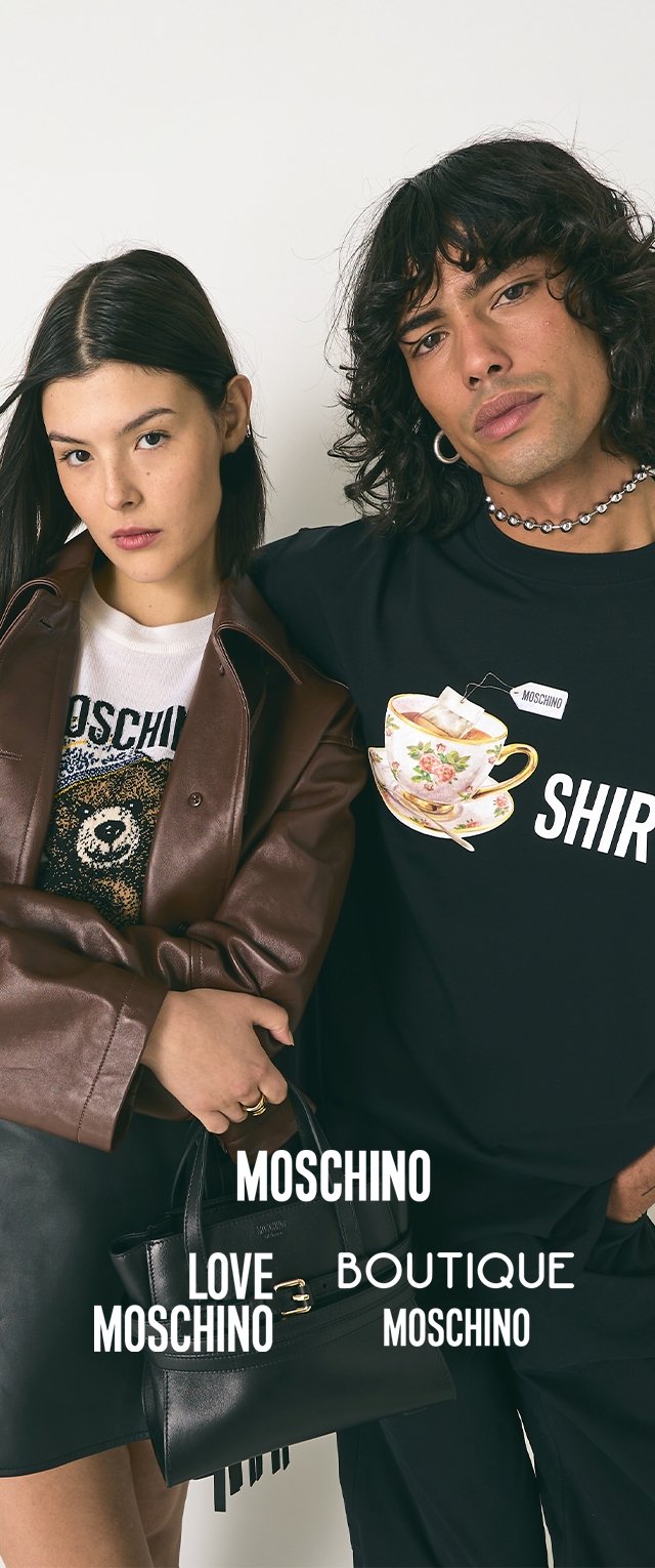 Junge Frau in Lederjacke, die eine schwarze Tasche hält, und Mann in schwarzem Hemd mit Teetasse-Design stehen eng beieinander vor weißem Hintergrund.