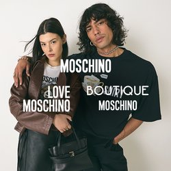 Mladý muž s kudrnatými vlasy v černém tričku s potiskem má paži přes ramena ženy, která nosí hnědý kabát, černou sukni a drží černou kabelku.