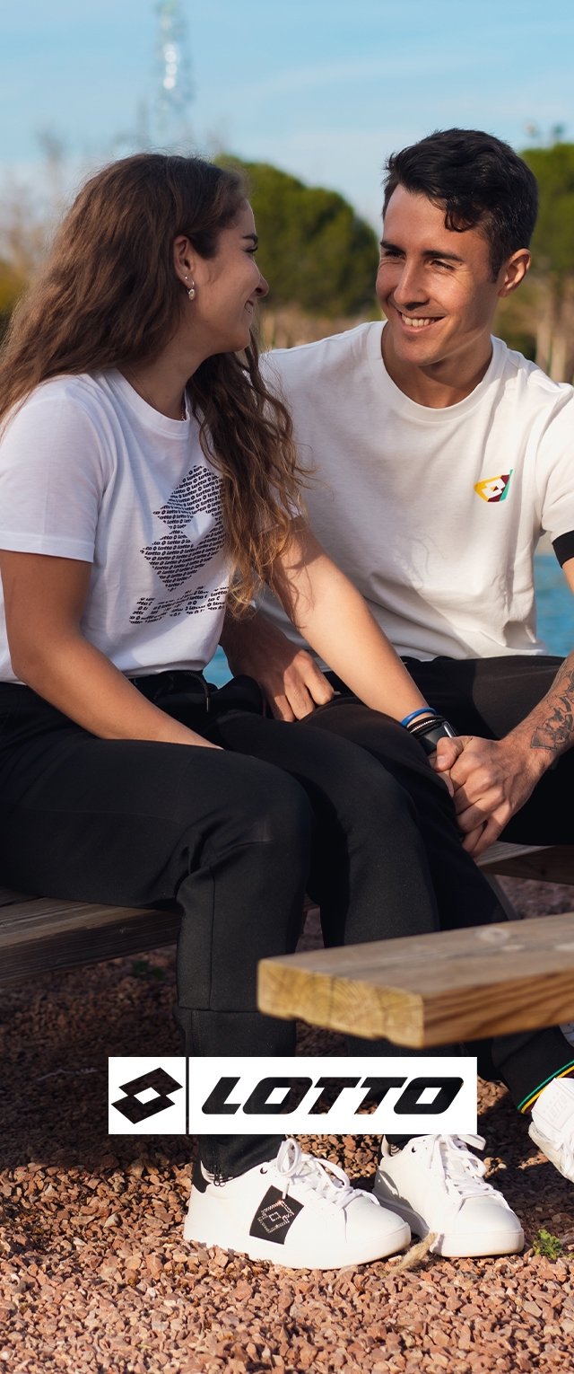 White Lotto sneakers with black accents, black pants, and graphic tees on a wooden bench with a background of greenery and water.