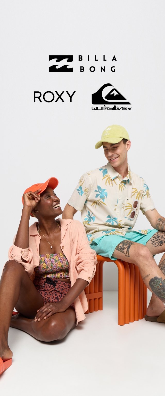 Dos personas se sientan en un taburete naranja, vestidas con coloridos atuendos de verano. Uno lleva una camisa de flores y shorts azules cortos; el otro, un bañador estampado con shorts.