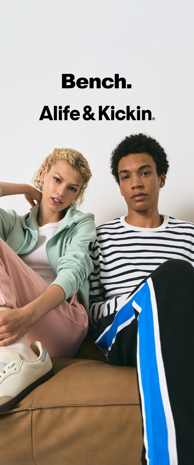 Zwei junge Erwachsene sitzen auf einer braunen Couch; Frau in einem mintfarbenen Kapuzenpullover und rosa Hose, Mann in einem gestreiften Hemd und blau gestreiften Hosen, Markenlogos über ihnen.