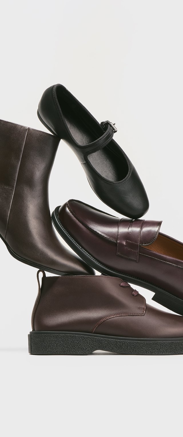 Four pairs of shoes stacked: a brown leather ankle boot, a black ballet flat, a burgundy loafer, and a dark burgundy lace-up shoe, all smooth-textured.