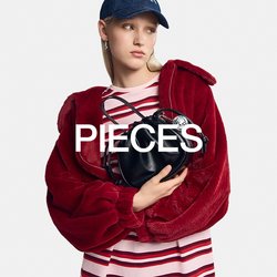 Černá kožená kabelka zaobleného tvaru s šňůrkovým uzávěrem, držena proti červené umělé kožešině a pruhovanému růžovo-bílému tričku.