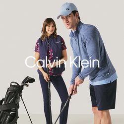 Muž a žena připravující se na hraní golfu v interiéru s golfovými holemi a golfovou taškou na neutrálním pozadí.
