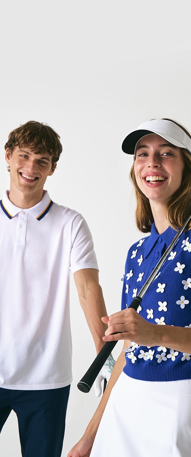 Weißes Poloshirt mit blauem und gelbem Kragen, kombiniert mit einem blauen Pullover mit weißen Blumenmustern und einem weißen Rock. Schwarzer Golfclub-Griff.