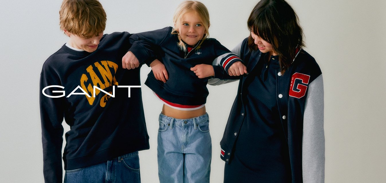 Dva teenageři a dítě stojí na židli. Teenageři mají na sobě tmavé mikiny; jeden z nich má logo. Dítě má na sobě krátký top a světlé džíny.