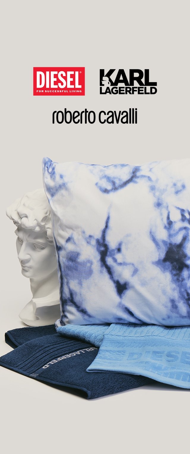 Escultura de busto detrás de un cojín teñido anudado azul y blanco y toallas dobladas con los logotipos de Karl Lagerfeld y Diesel visibles encima.
