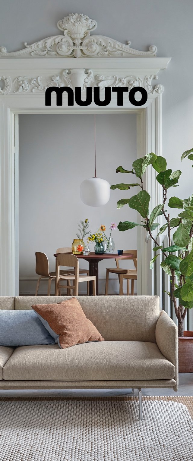 Sofa with a beige fabric upholstery, silver metal legs, featuring blue and rust-colored cushions. A patterned rug and greenery in the background.