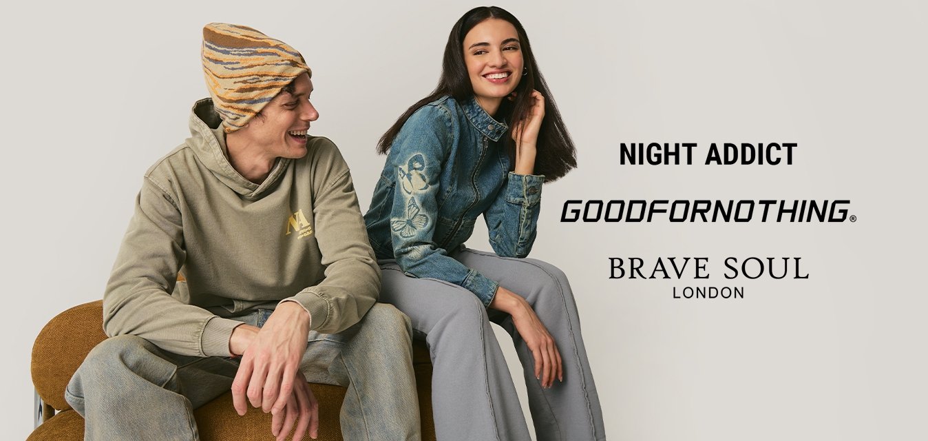 Mladý muž v čepici a mikině sedí vedle usměvavé ženy v modré džínové bundě a šedých kalhotách na neutrálním pozadí.