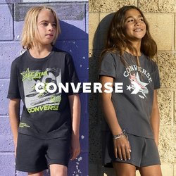 Dvě děti v tričkách s potiskem Converse a kraťasech stojí u texturovaných zdí, jedné fialové a jedné béžové, usmívají se a dívají se stranou.