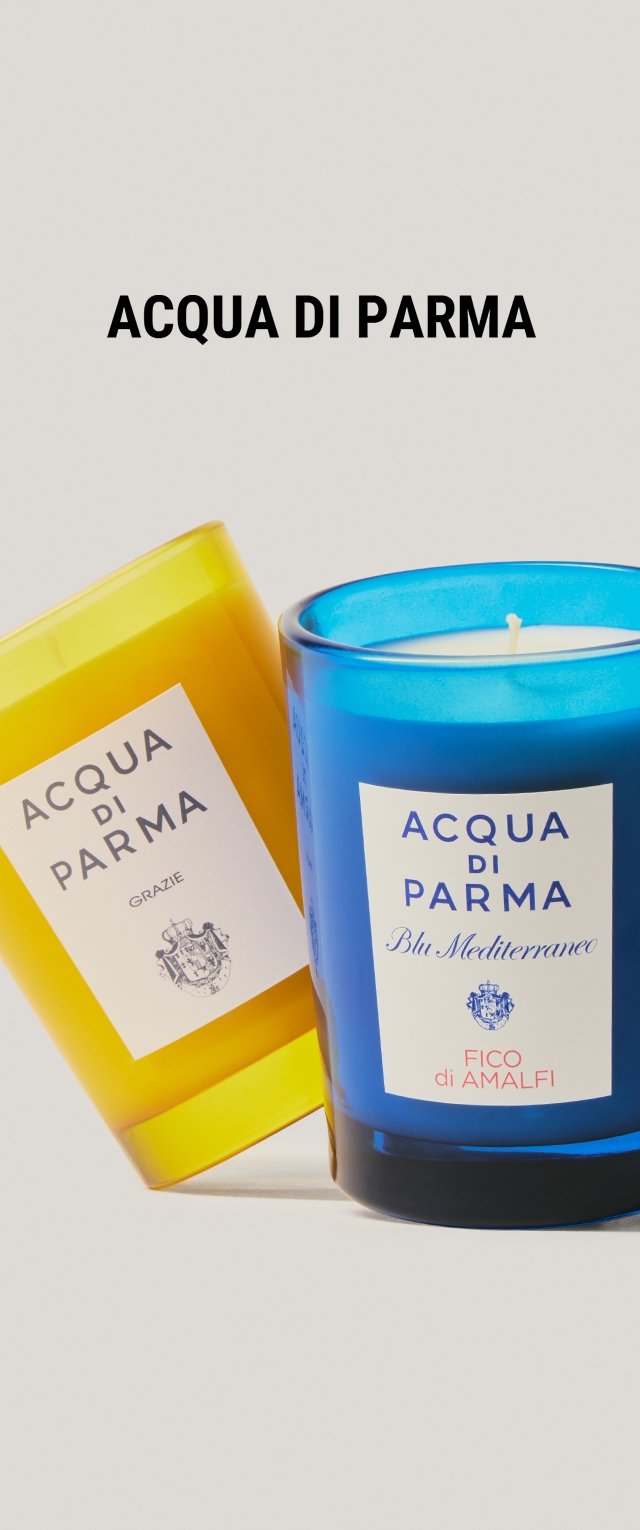 Dos velas: una amarilla con una etiqueta blanca que dice "Acqua di Parma Grazie," y una azul con una etiqueta que indica "Acqua di Parma Blu Mediterraneo Fico di Amalfi."