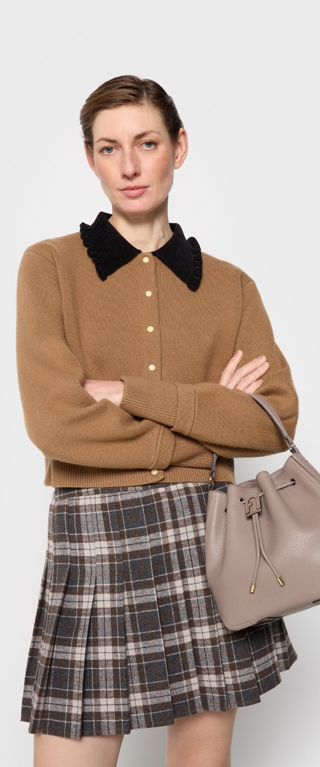 Hnedý vlnený kardigán s čiernym golierom a zlat ými gombíkmi. Šedá kockovaná plisovaná sukňa. Šedá textúrovaná kabelka so šnúrkou.