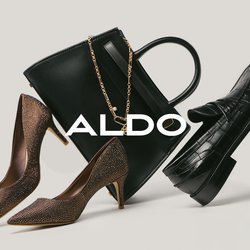 Pár hnědých vysokých podpatků, černá kožená kabelka se zlatým řetízkem a černá mokasína s krokodýlím vzorem na neutrálním pozadí.