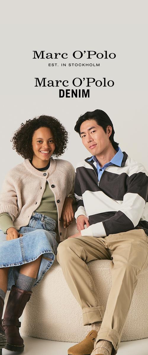 Twee modellen zitten samen op een lichtbeige oppervlak. De vrouw draagt een crèmekleurige cardigan over een groene top, met blauwe denim jeans en bruine laarzen. De man draagt een gestreepte pullover in zwart, wit en blauw over een blauwe blouse, met kaki broek en beige schoenen.