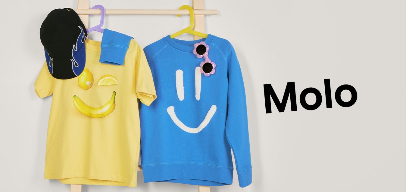 Žluté tričko s úsměvem a černá kšiltovka, modrá mikina s bílým úsměvem a růžovými slunečními brýlemi visí na dřevěném stojanu.