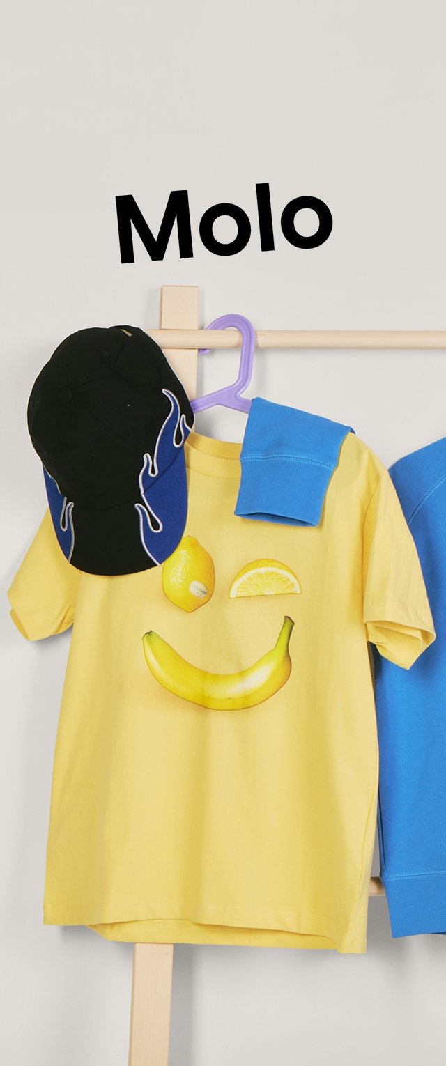 Keltainen T-paita, jossa hedelmäinen hymyprintti, musta ja sininen lippis sekä sininen taitettu hiha roikkuvat puisella naulakolla, jonka yläpuolella on Molo-merkkinen logo.