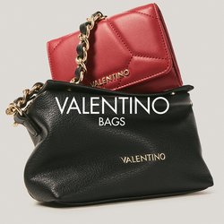 Černá kožená kabelka Valentino se zlatým řetízkovým popruhem a červenou peněženkou Valentino částečně uvnitř na jednobarevném pozadí.