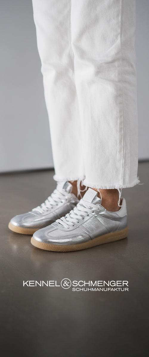 Sølv lærersneakers med en glatt tekstur, hvite snørebånd og en lys brun gummisal, kombinert med utappede hvite jeans.