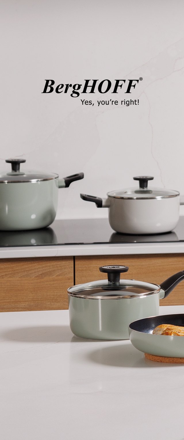 Drei grüne und weiße Töpfe mit Deckeln und eine Bratpfanne mit Essen auf einer weißen Arbeitsplatte, im Hintergrund ein Herd und Holzmöbel.