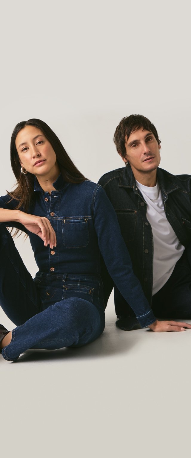 Dwie modele noszą dżinsowe kreacje: ciemnoniebieski kombinezon z wysokim kołnierzem i przednimi kieszeniami oraz kurtka dżinsowa na białej koszuli.