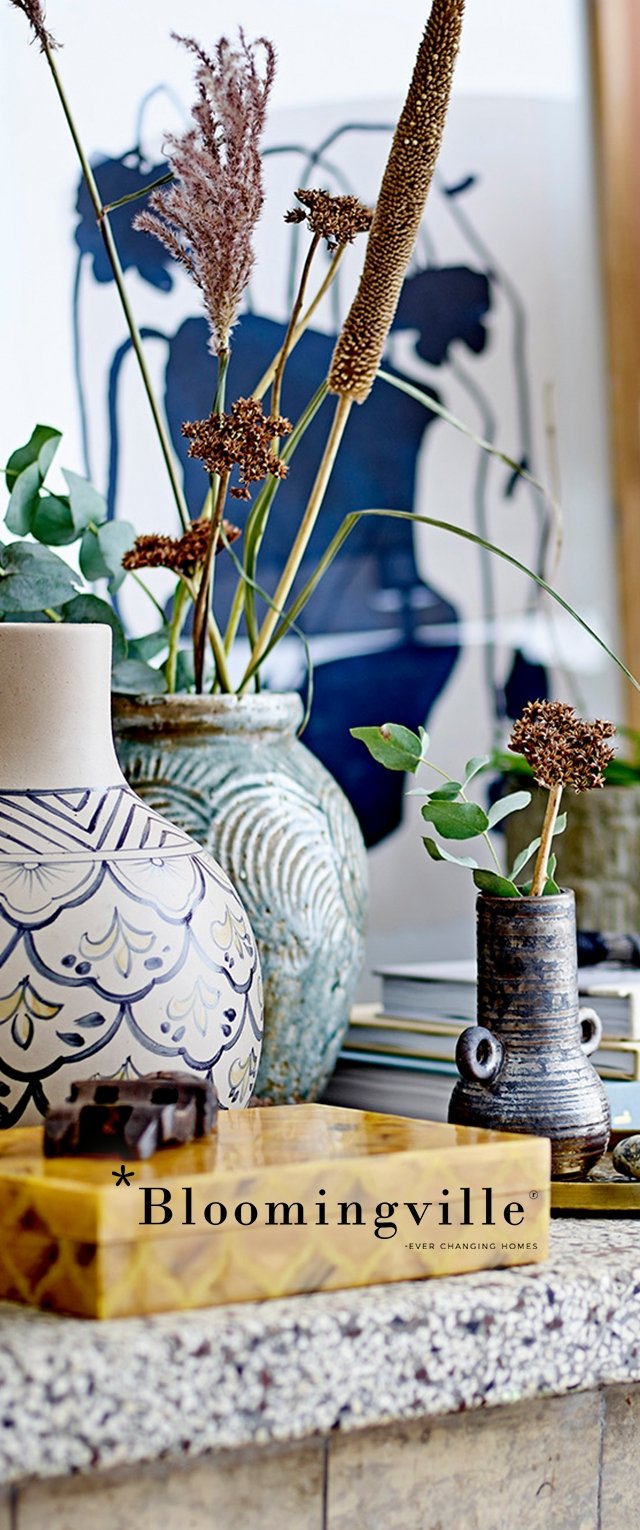 Jarrones decorativos verdes y beige con superficies texturizadas, flores secas y una caja amarilla decorada sobre una encimera moteada.