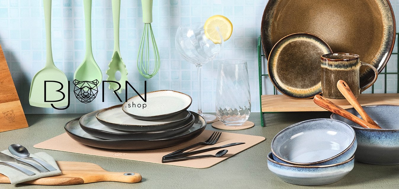 Čtyři zelené kuchyňské náčiní visí, nože v dřevěném bloku, naskládané keramické talíře a mísy, sklenice s plátkem citronu a dřevěné lžíce.