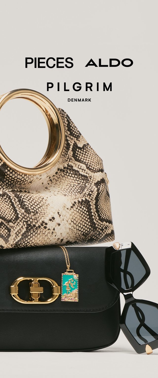 Bolso de piel de serpiente con acento dorado, apilado sobre un bolso de cuero negro con un broche dorado y un charm decorativo. Gafas de sol negras con forma única.