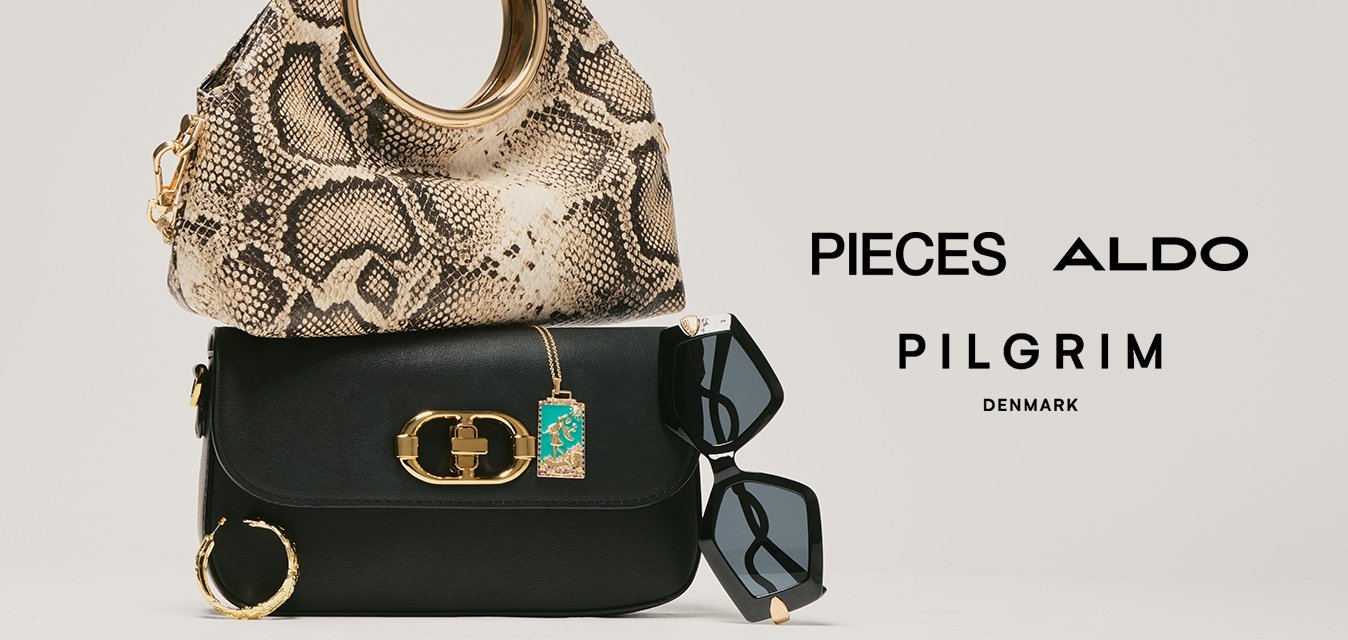 Dvě kabelky naskládané na sobě, nahoře kabelka s hadím vzorem a pod ní černá kabelka, doplněné o černé sluneční brýle a zlaté kruhové náušnice.