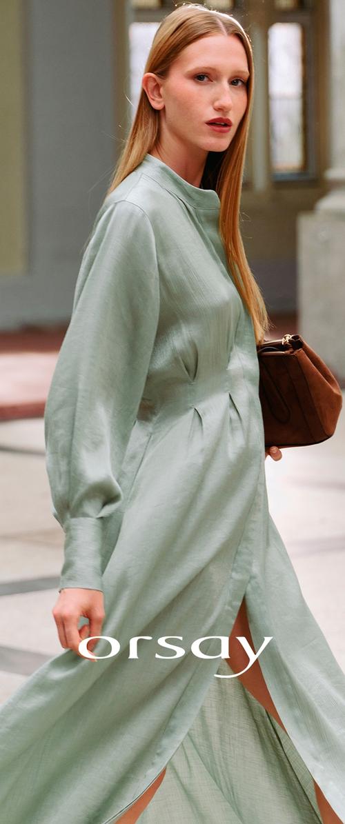 Long-sleeve, light green dress with a high collar, pleated details, and side slit, paired with a brown handbag. Smooth fabric texture.