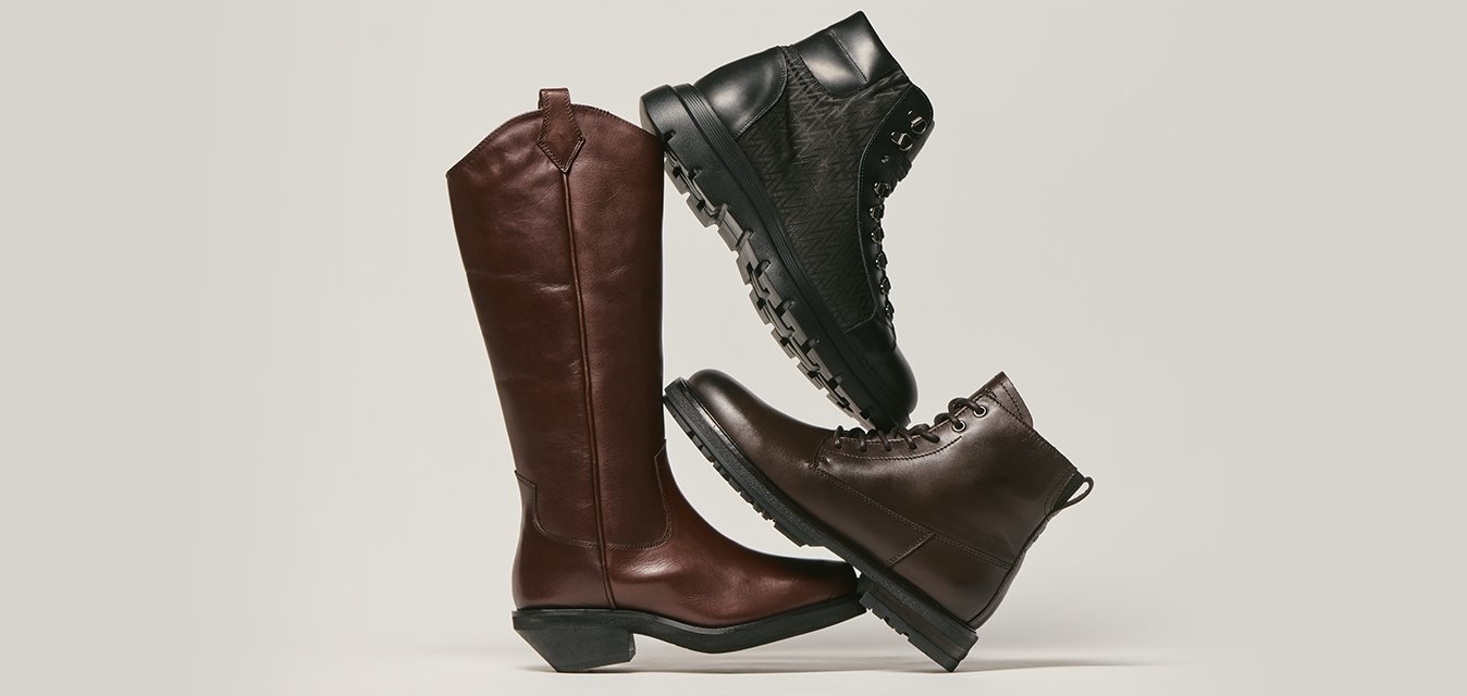 Tři naskládané kožené boty: jedny vysoké hnědé jezdecké boty, jedny černé turistické boty a jedny tmavě hnědé kotníkové boty.