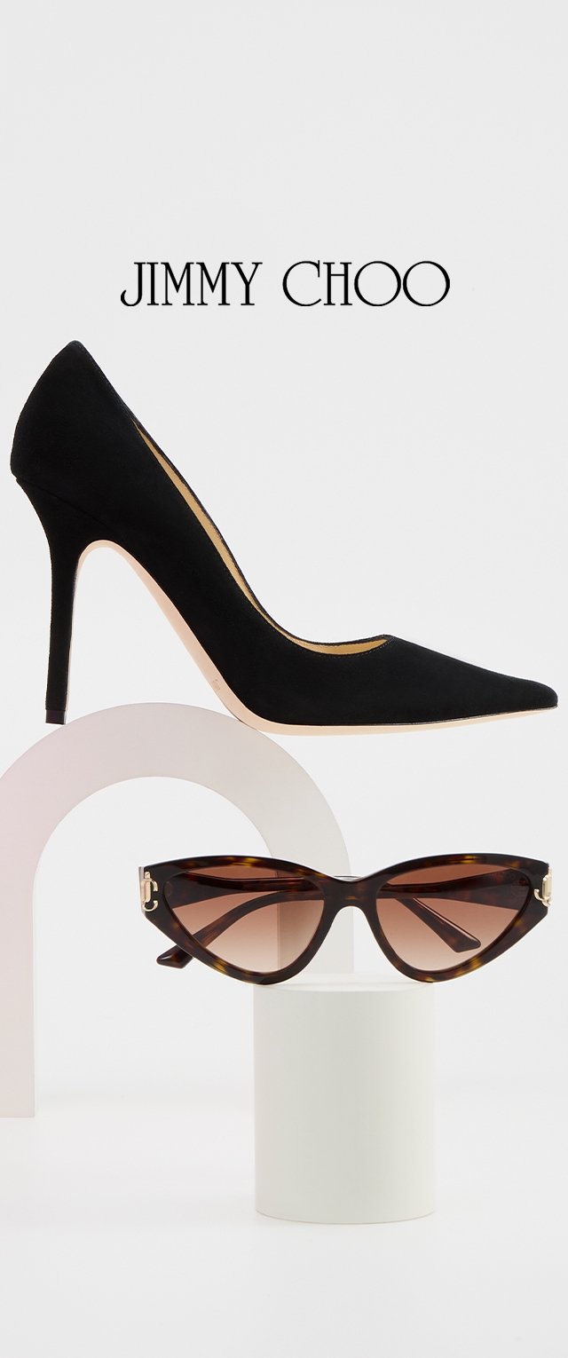 Pump neri in suede con tacco alto e punta appuntita, sopra occhiali da sole a forma di occhi di gatto in tartaruga con lenti sfumate, esposti su basi minimali.