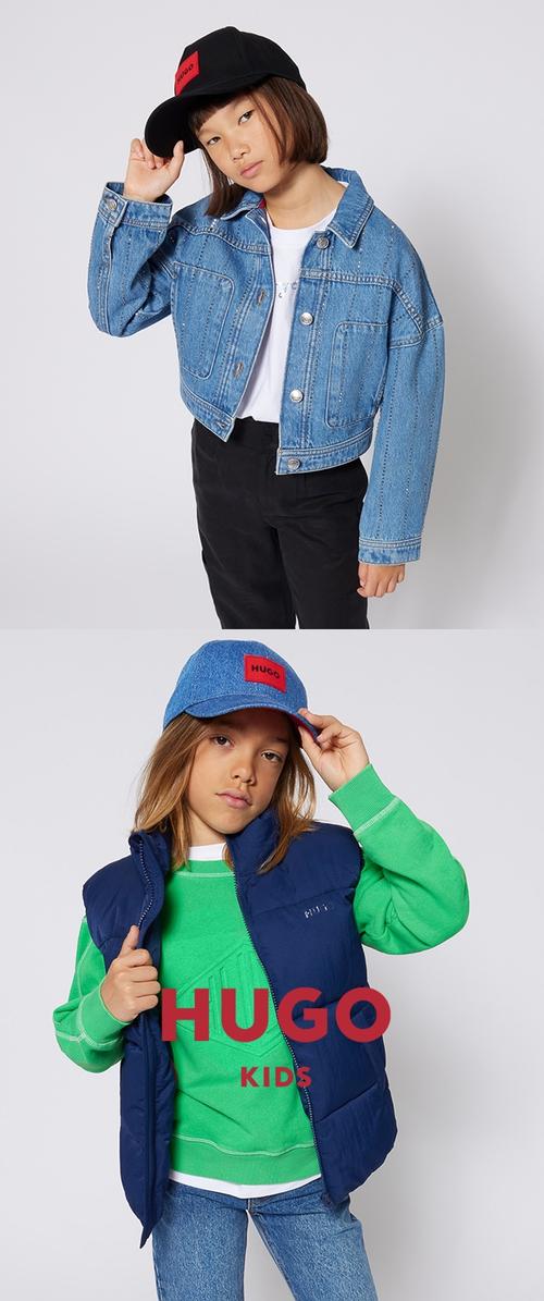 To børn poserer iført afslappede HUGO-kasketter og overtøj: den ene i en denimjakke og sorte bukser, den anden i en blå vest og grøn sweatshirt.