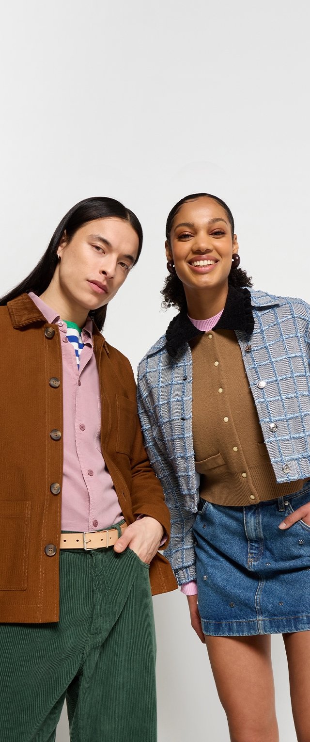 Twee mensen staan samen in gecoördineerde outfits. De één draagt een bruine corduroy jas, een roze shirt, groene corduroy broek en een riem. De ander draagt een geruite blauwe cropped jas, een bruine trui en een denim rok met versieringen.