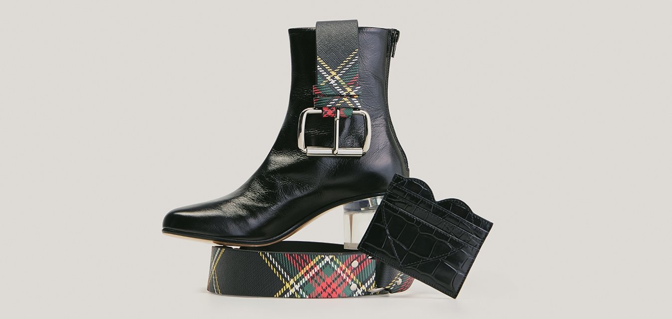 Černá kožená kotníková bota s průhledným podpatkem, kostkovaným páskem a černou peněženkou s krokodýlím vzorem na neutrálním pozadí.