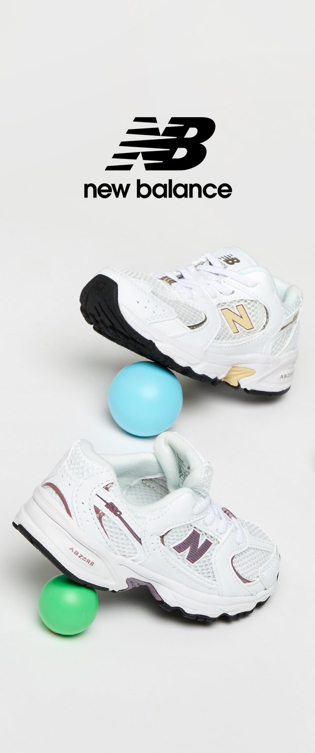 Baskets New Balance blanches avec des accents violets et dorés, dotées d'un matériau en maille et d'une semelle en caoutchouc texturé, posées sur des ballons colorés.