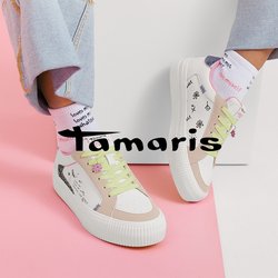 Osoba nosící světlé džínové kalhoty, bílé tenisky s pastelově zelenými tkaničkami a ručně psanými vzory a bílé ponožky s červeným textem.