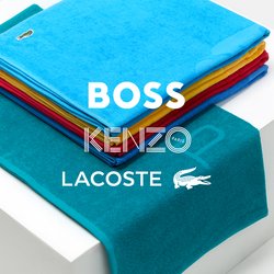 Sada tyrkysových ručníků, zahrnující hromadu barevných utěrek v červené, žluté a modré, umístěných na bílé krabici s texturovaným tyrkysovým ručníkem přehozeným vedle.