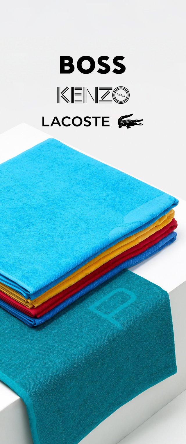 Pila di asciugamani colorati: blu, giallo, rosso e turchese, realizzati in un morbido tessuto. L'asciugamano turchese presenta un motivo sottile ed è in evidenza.