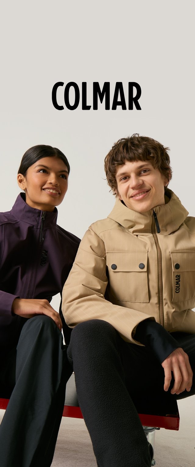 Dos modelos sonrientes que llevan chaquetas Colmar, una en beige con bolsillos delanteros y la otra en púrpura oscuro con detalle de cremallera, sentados frente a un fondo liso.