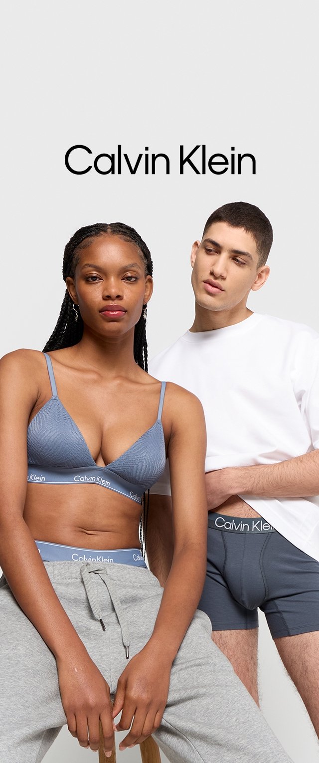 Grauer Sport-BH mit strukturiertem Muster und hellblauen Akzenten, kombiniert mit grauen Jogginghosen. Model trägt graue Unterwäsche mit einem Logo auf dem Bund.