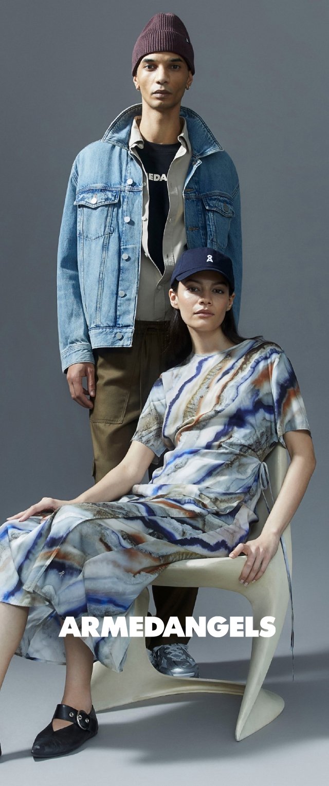 Zwei Models tragen zeitgenössische Outfits. Das männliche Model trägt eine hellblaue Jeansjacke und eine dunkle Mütze, während das weibliche Model ein gemustertes Kleid trägt.