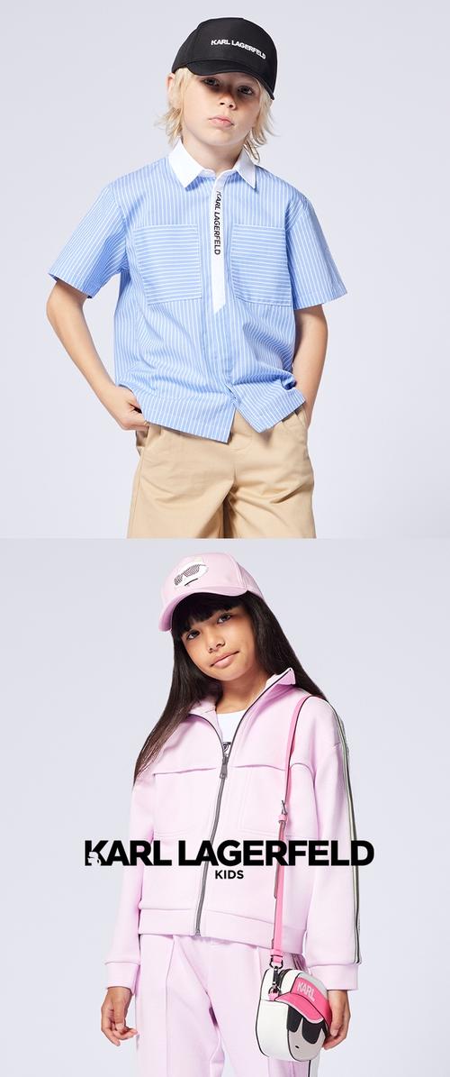 Niño rubio con camisa azul a rayas y gorra negra, niña con chándal rosa, gorra y bolso de dibujos animados, ambos sobre fondo gris claro.
