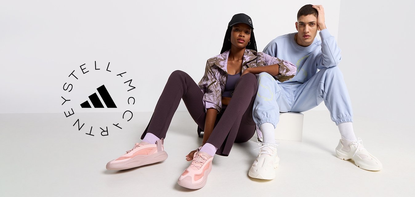 Dva modely sedí na světlém povrchu. Jeden má na sobě vzorovanou hnědou bundu, fialové legíny a růžové tenisky. Druhý je oblečený ve světle modrém teplákovém setu a bílých teniskách.