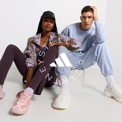 Dva modely sedí na světlém povrchu. Jeden má na sobě vzorovanou hnědou bundu, fialové legíny a růžové tenisky. Druhý je oblečený ve světle modrém teplákovém setu a bílých teniskách.